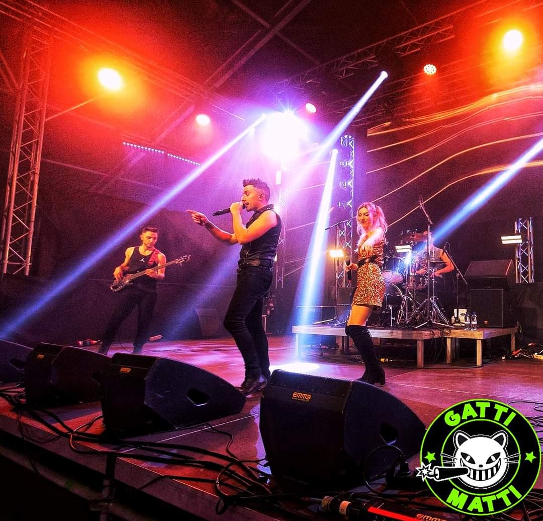 gatti matti live sul palco con logo gatti matti in basso a destra